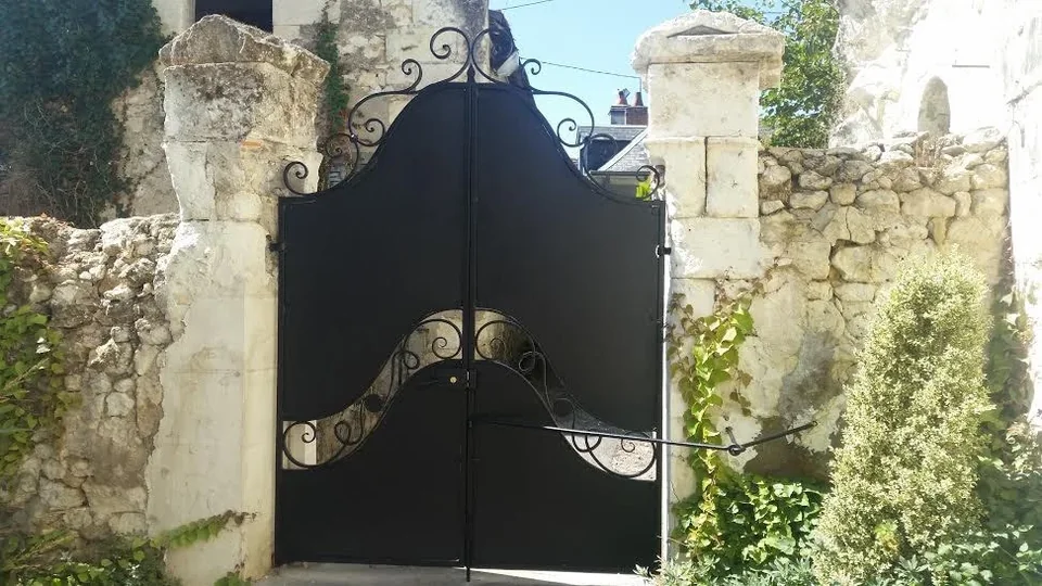 Portail noir entre deux piliers en pierre